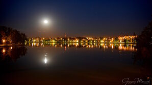 Bild der beleuchteten Stadt Ilawa und des kleinen Geserichsees bei Nacht mit Vollmond