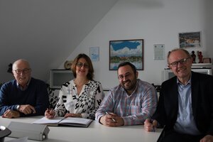 Vier Personen an einem Tisch: Vertragsunterzeichnung Windpark