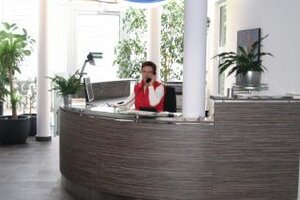 Eine Mitarbeiterin sitzt am Empfang und telefoniert 