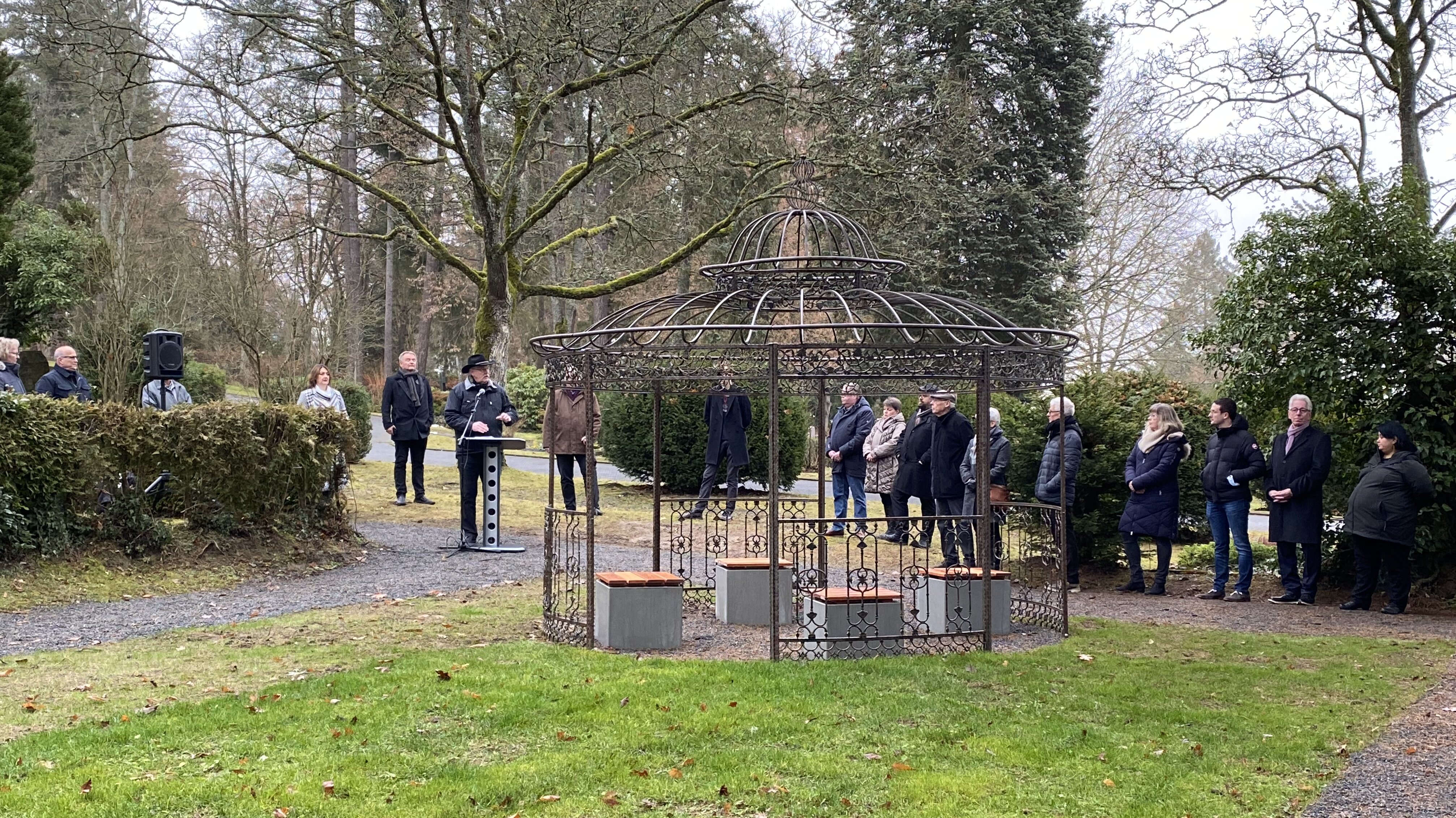 Menschen stehen auf dem Friedhof Herborn zur Widmung des Gedenkplatzes für Sternenkinder