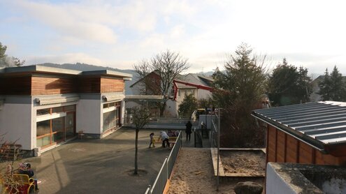 Außenansicht der Kita Mozartstraße, im Hintergrund ist ein Landschaftsgärtner  beim Fällen eines Kastanienbaumes zu sehen.