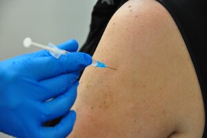 Corona-Schutzimpfung, behandschuhte Hand mit Spritz an Oberarm 