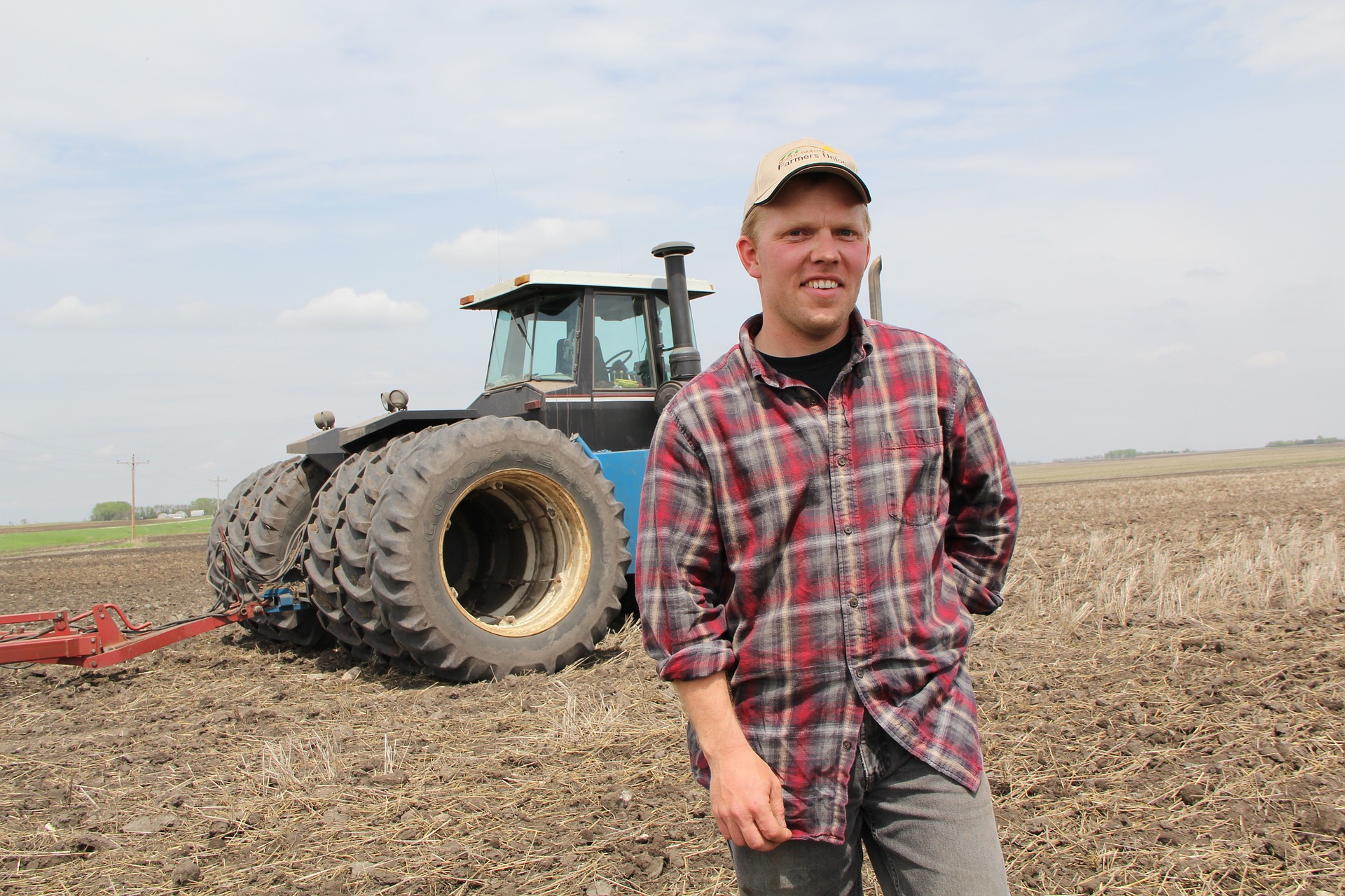 Landwirt vor einem Traktor auf einem Feld.