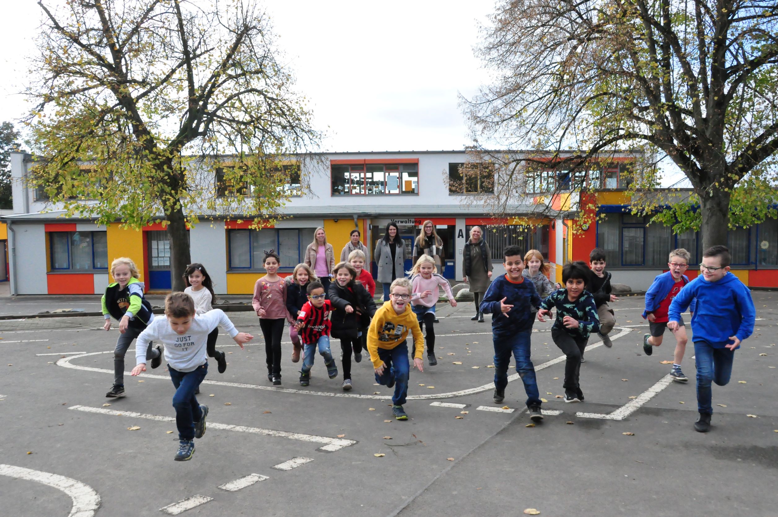 Schülerinnen und Schüler rennen auf dem Pausenhof.