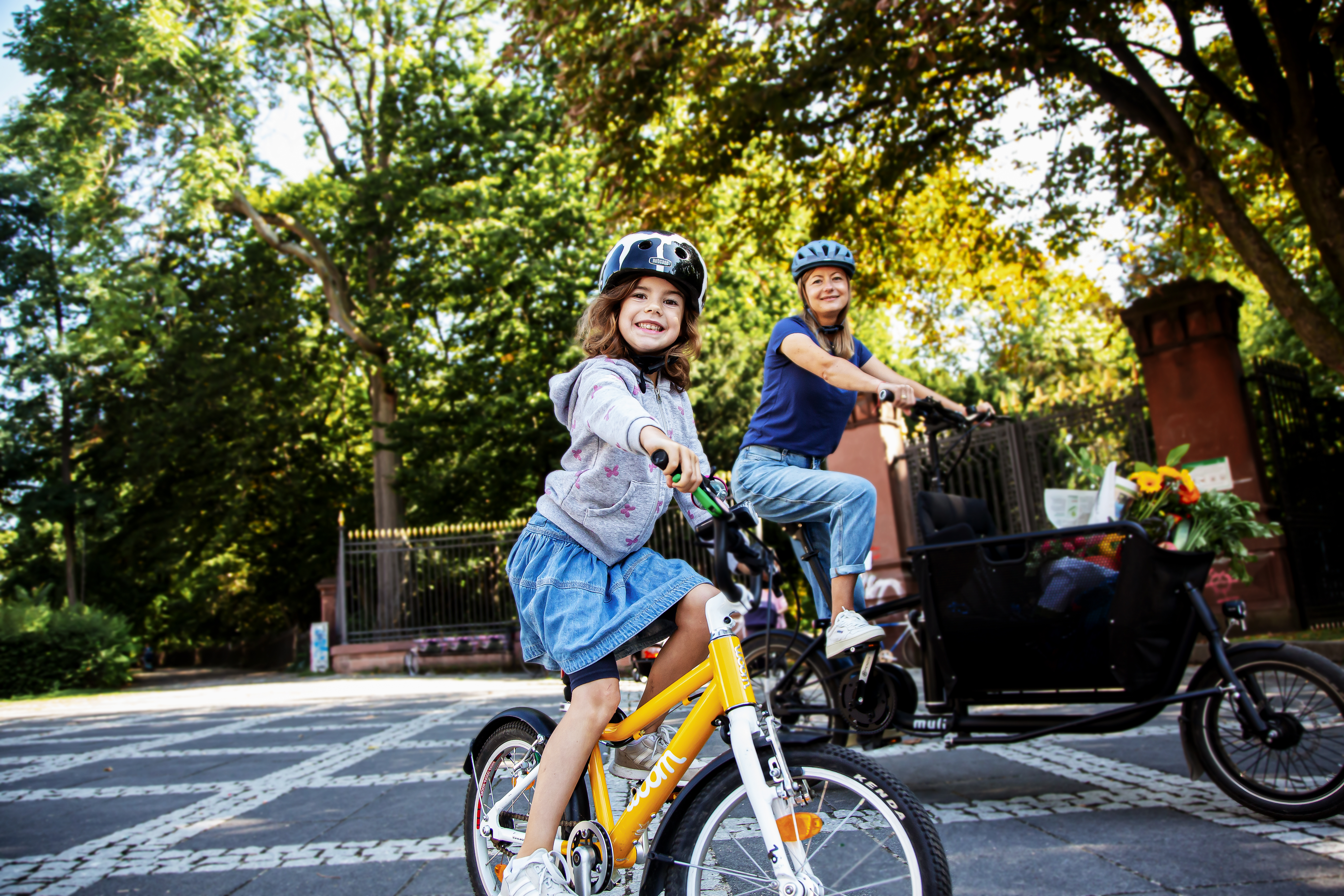 Frau mit Lastenrad und Kind mit Fahrrad.